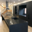 Open concept kitchen with a black waterfall island, pendant lights, and matte-black cabinetry.
