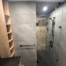 Walk-in glass shower with large grey wall tiles, black fixtures, and a built-in niche.